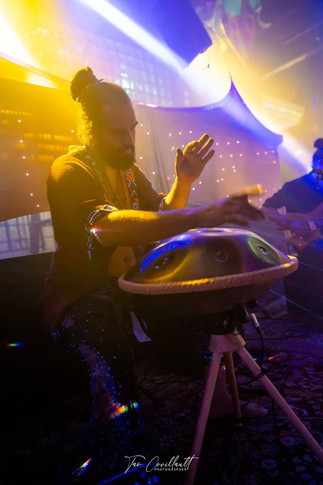 A musician playing handpan in golden light during the sound journey