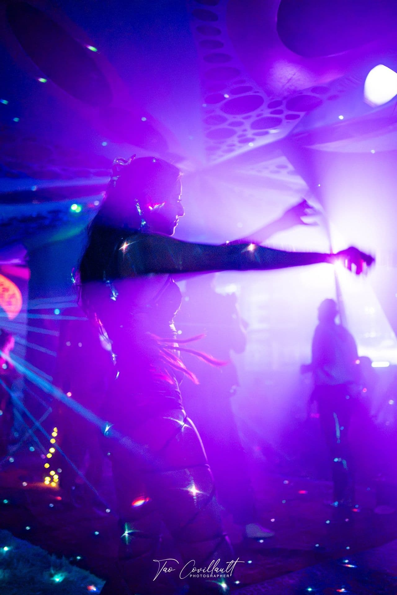 A dancer stretching an arm out through violet haze